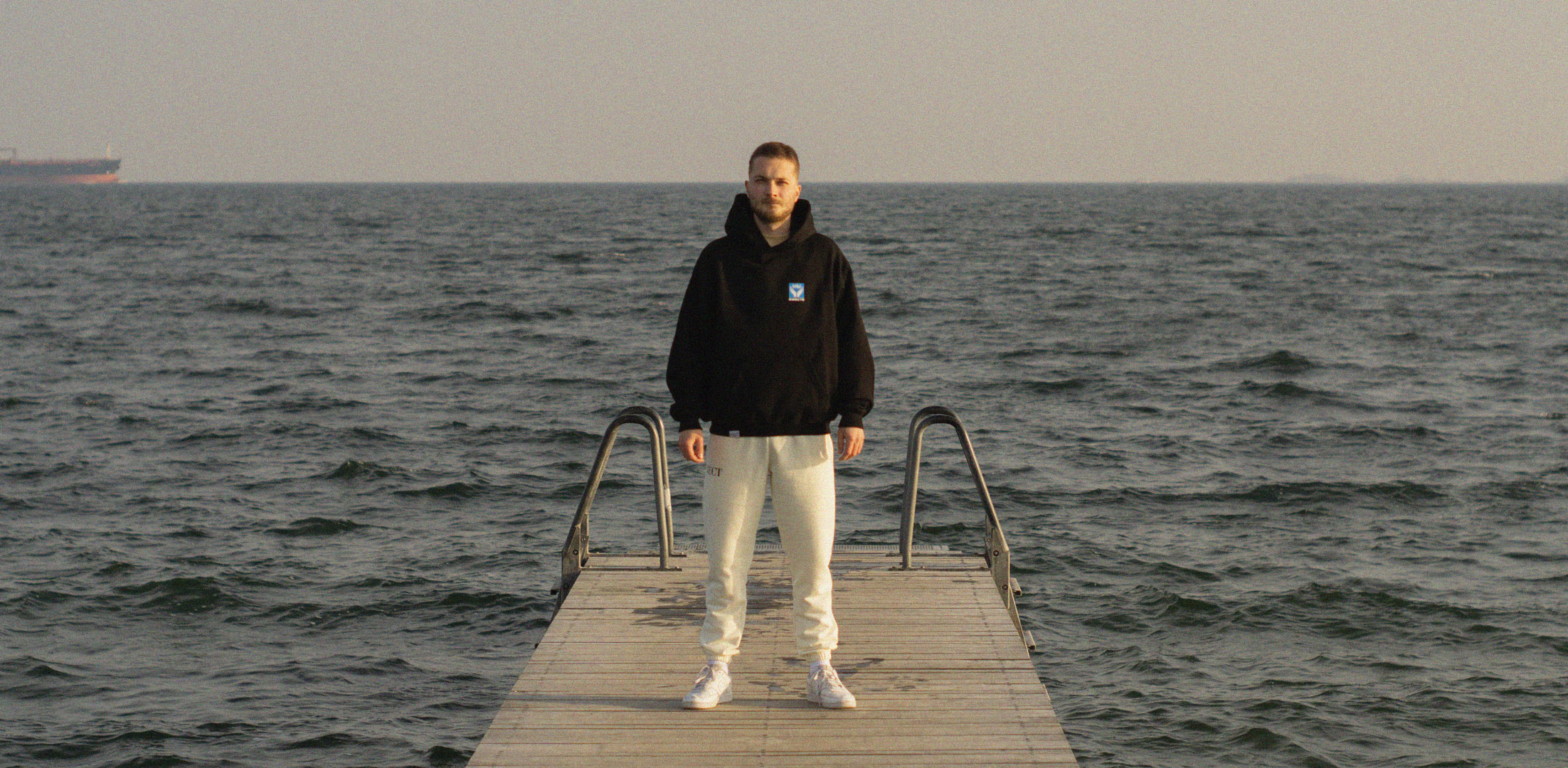 Male Model with BECT We Are Together hoodie at Amager beach (Strandpark) in Copenhagen, Denmark, with the ocean in the background